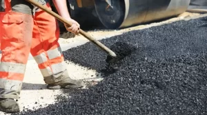 person shoveling asphalt on road